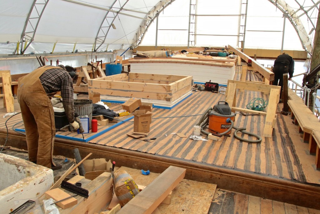 The new Douglas fir aft deck is sealed.  Now the sealant is being applied where the planking meets the break in the deck which steps down to the foredeck. The platform masked in blue is where the opening for the main mast will pass through to the mast step on the keel. credit Robert Mitchell