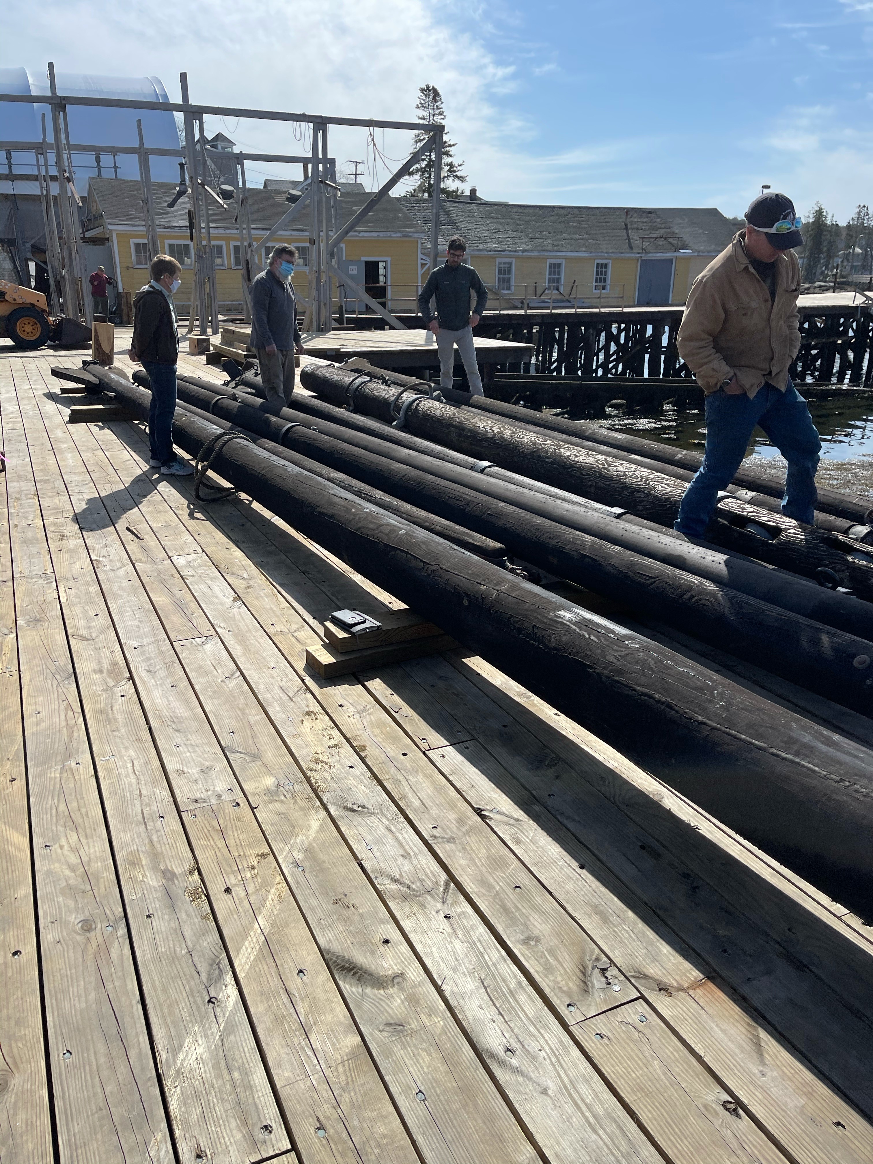 20210415 spars at shipyard The spars were delivered to the Shipyard where they were inspected by Captain Tiffany Krihwan, Shipwright David Short, Project Manager Dennis Gunderson and Tom Ward, the rigging contractor. After a thorough inspection of their condition a decision will be made to use them or to take the hardware off and make new spars.