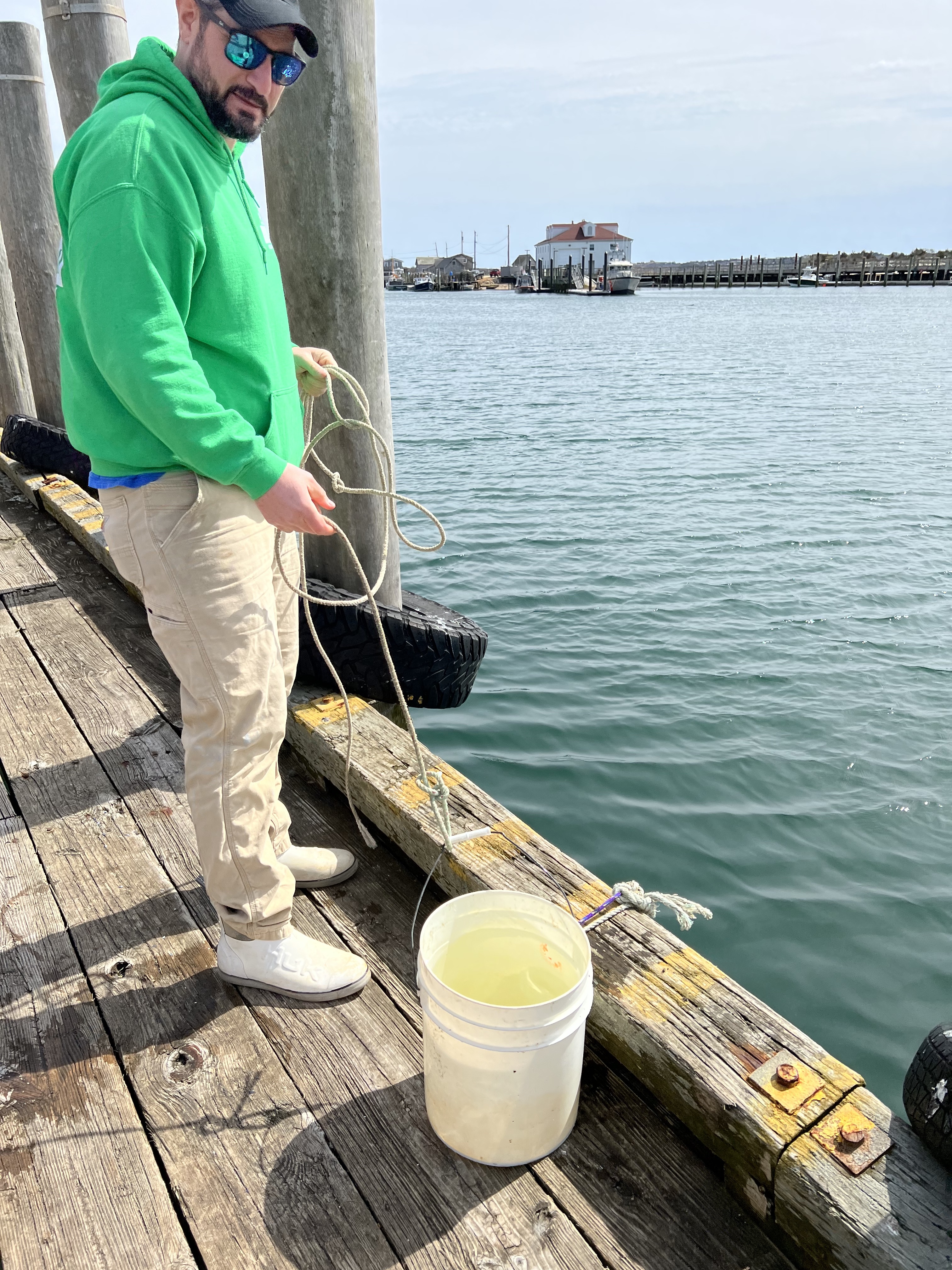 Peter Lambos collects water from Menemsha Harbor where Fred Littleton was Harbor Master.