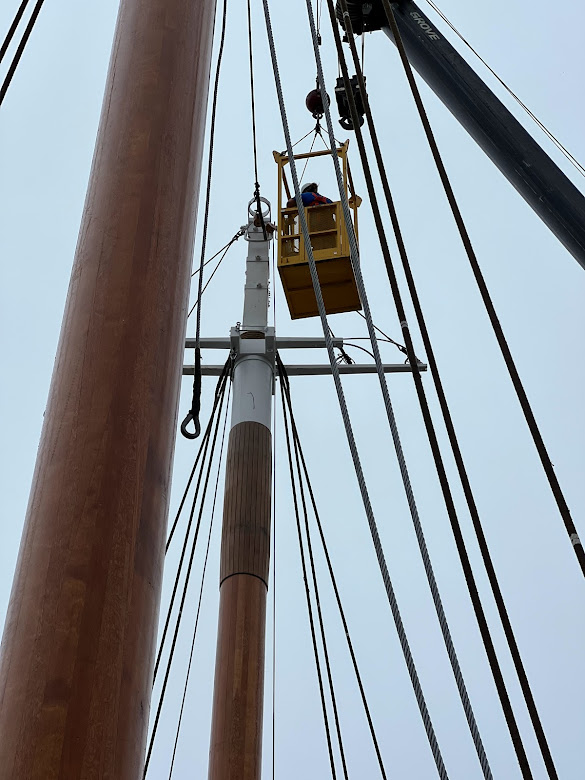 Crew aloft rigging stays.
