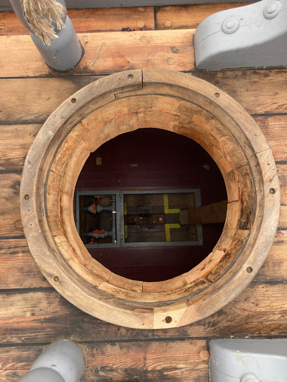 Looking through the hole in the deck ready to receive the mast. In the mortise below, which will receive the mast's tenon, you can some of the coins placed there.